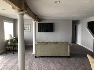 Mariners Cove cottage في نورفولك: غرفة معيشة مع أريكة وتلفزيون على الحائط