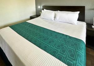 Cama en habitación de hotel con manta verde y blanca en InHouse Obregón en Ciudad Obregón