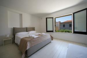 une chambre blanche avec un lit et une fenêtre dans l'établissement Scudaniglio Apartments, à Trapani