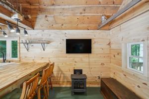 a log cabin with a fireplace and a television and a stove at Gloversville Retreat with Patio and Lake Access! in Gloversville