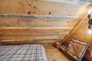 a bedroom with a bed and a wooden wall at Gloversville Retreat with Patio and Lake Access! in Gloversville