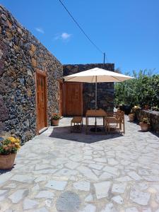 Isora的住宿－Casa Rural LUCÍA，一个带桌子和遮阳伞的庭院