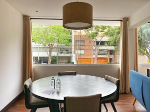 comedor con mesa y sillas y ventana grande en Luxury 2BR in Blas Cerdeña San Isidro, en Lima