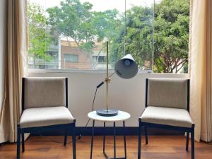 dos sillas y una lámpara en una mesa frente a una ventana en Luxury 2BR in Blas Cerdeña San Isidro, en Lima