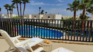 una piscina con due sedie bianche accanto a una recinzione di PARADISE premium apartment a Villajoyosa