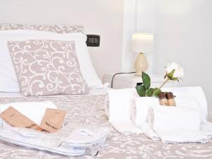 ein weißes Bett mit Handtüchern und einer Blume darauf in der Unterkunft Puccio Home Stadio - City Center in Verona