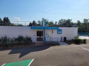 a white building with a gate and a parking lot at KYRIAD DIRECT LYON NORD - Dardilly in Dardilly