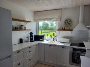 uma cozinha com armários brancos, um lavatório e uma janela em Kaldeni majutus em Are