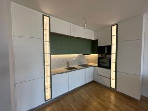 a kitchen with white and green cabinets and wood floors at Skyline Apartment 1 in Peje