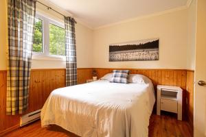 sypialnia z łóżkiem i oknem w obiekcie Les Chalets Tourisma - Chalet au bord de l'eau avec spa et foyer - Le Draveur w mieście Saint-Raymond