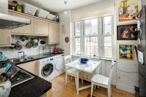 a kitchen with a washing machine and a table at Stylish Central London Flat Near Tower Bridge in London