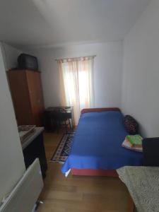 sypialnia z niebieskim łóżkiem i oknem w obiekcie Apartments Berbić w Szybeniku