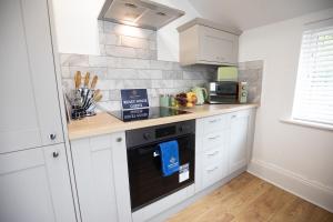 a kitchen with white cabinets and a black oven at Ridley House Apartments in Yarm