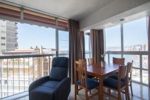 a dining room with a table and chairs and large windows at Apartamentos Las Carabelas in Benidorm