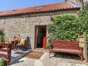 a wooden bench in front of a brick building at Daffodil Cottage in Danby