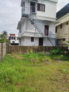 een wit huis met een trap aan de zijkant bij Micro homestay mulavukad in Ernakulam