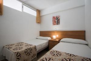 two beds in a small room with a window at Apartamentos Las Carabelas in Benidorm