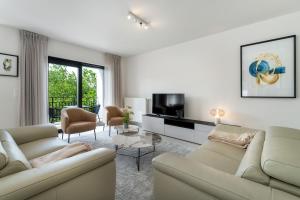 een woonkamer met 2 banken en een tv bij Zonnig Luxueuze Appartementen La Coronne in Knokke-Heist