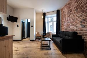 a living room with a black couch and a brick wall at Dream Apartments - Gdańska 72 in Łódź