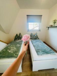 a person holding a bouquet of flowers next to two beds at Albergue Haid 
