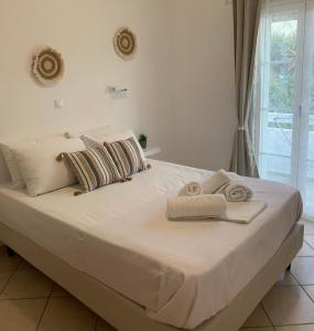 Una gran cama blanca con toallas encima. en Fabrika Apartments, en Vári