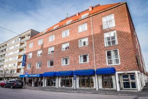a large brick building with blue awnings on a street at Hotel Amadeus in Halmstad