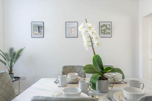 a dining room table with white dishes and a plant at Charming 3-Bedroom Home in Historic Lincoln Ideal for Families in Lincolnshire