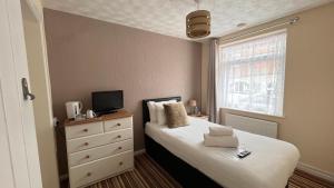 a bedroom with a bed and a dresser and a window at Tusker Lodge in Torquay