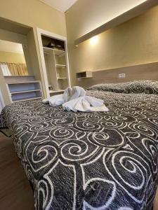 een groot bed met een zwart-witte deken erop bij Hotel Sialdorf in Villa Carlos Paz