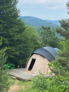 une tente avec une terrasse en bois dans les bois dans l'établissement SIMBIOSIS. Agri Cultur'Art Camp, à Pontinvrea