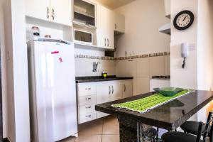 eine Küche mit einem weißen Kühlschrank und einem Tisch in der Unterkunft Duplex na beira da praia, de frente pro mar in Salvador