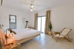 um quarto com uma cama, uma cadeira e uma janela em Exotic Shanty Villa Casa Mia em Eilat