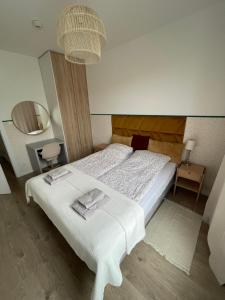 1 dormitorio con cama blanca y espejo en Modern Tower Apartament Gdynia, en Gdynia