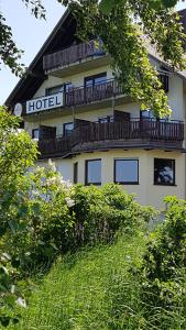 ein Hotelgebäude mit einem Balkon auf der Seite in der Unterkunft Hotel Wildenburger Hof in Kempfeld