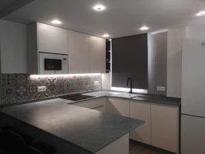 a kitchen with white cabinets and a black counter top at Apartamento a 1 MINUTO de la playa en GARRUCHA in Garrucha