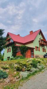 dom z czerwonym dachem na szczycie pola w obiekcie Chata Zieleniecka w mieście Duszniki Zdrój