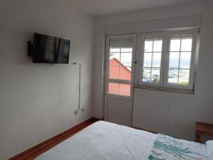 a bedroom with a bed and a tv on the wall at Las 4 columnas (MFA) in Muxia