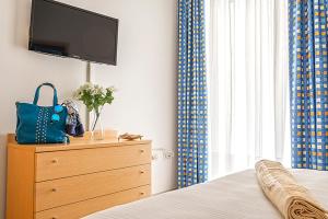 a bedroom with a dresser with a tv on top of a bed at Casa Lucia Centro Apartment Deluxe in Sottomarina +16 photos