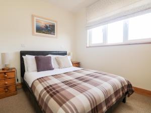 a bedroom with a bed with a plaid blanket and a window at Boslow in St. Just