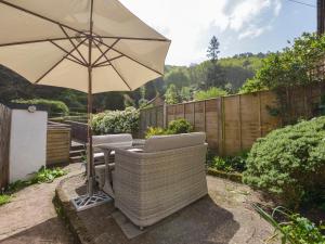 a patio with an umbrella and a table and chairs at Woodedge in Minehead