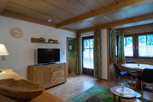 een woonkamer met een televisie en een tafel en stoelen bij Der Bräuschmied in Lofer