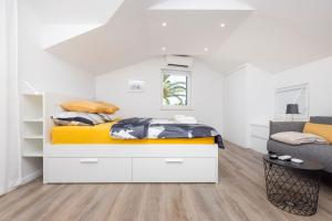a white bedroom with a bed and a chair at Easy in Mali Lošinj