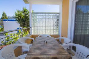 a wooden table and white chairs on a balcony at Villa Giorgos in Kefalos