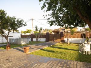 einen Hinterhof mit einem gemauerten Gehweg und einem Zaun in der Unterkunft Villa Alegría in Chiclana de la Frontera