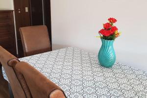 eine blaue Vase mit roten Blumen auf dem Tisch in der Unterkunft Furadouro Beach Apartment in Ovar + 3 Fotos