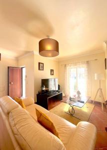 uma sala de estar com um sofá branco e uma televisão em casa de praia em Charneca
