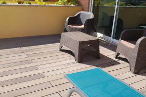 eine Terrasse mit Korbstühlen und einem Tisch und einer Bank in der Unterkunft Furadouro Beach Apartment in Ovar