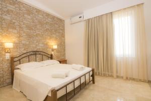 a bedroom with a large bed and a brick wall at Villa Giorgos in Kefalos