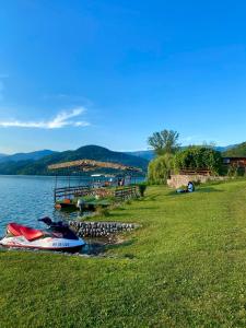 a boat parked on the shore of a lake at Rustic Heaven Ostrožac Cottage houses in Jablanica