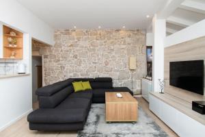 sala de estar con sofá negro y pared de piedra en Apartment Julija, en Vodice